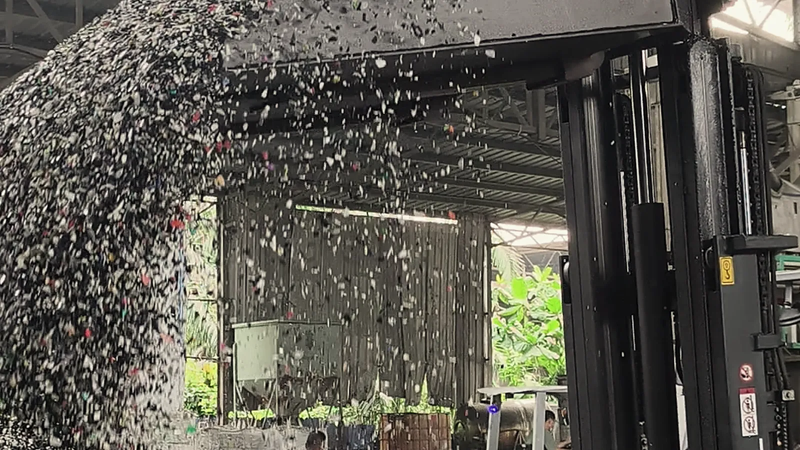 Plastic flakes cascading from a loader's bucket