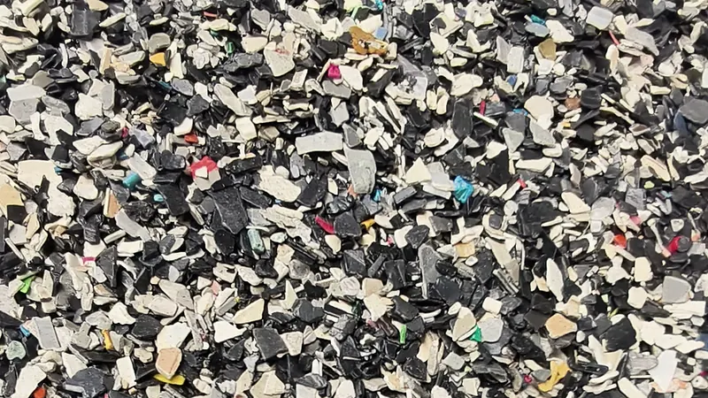 Mixed crushed plastic flakes of many colours, close up