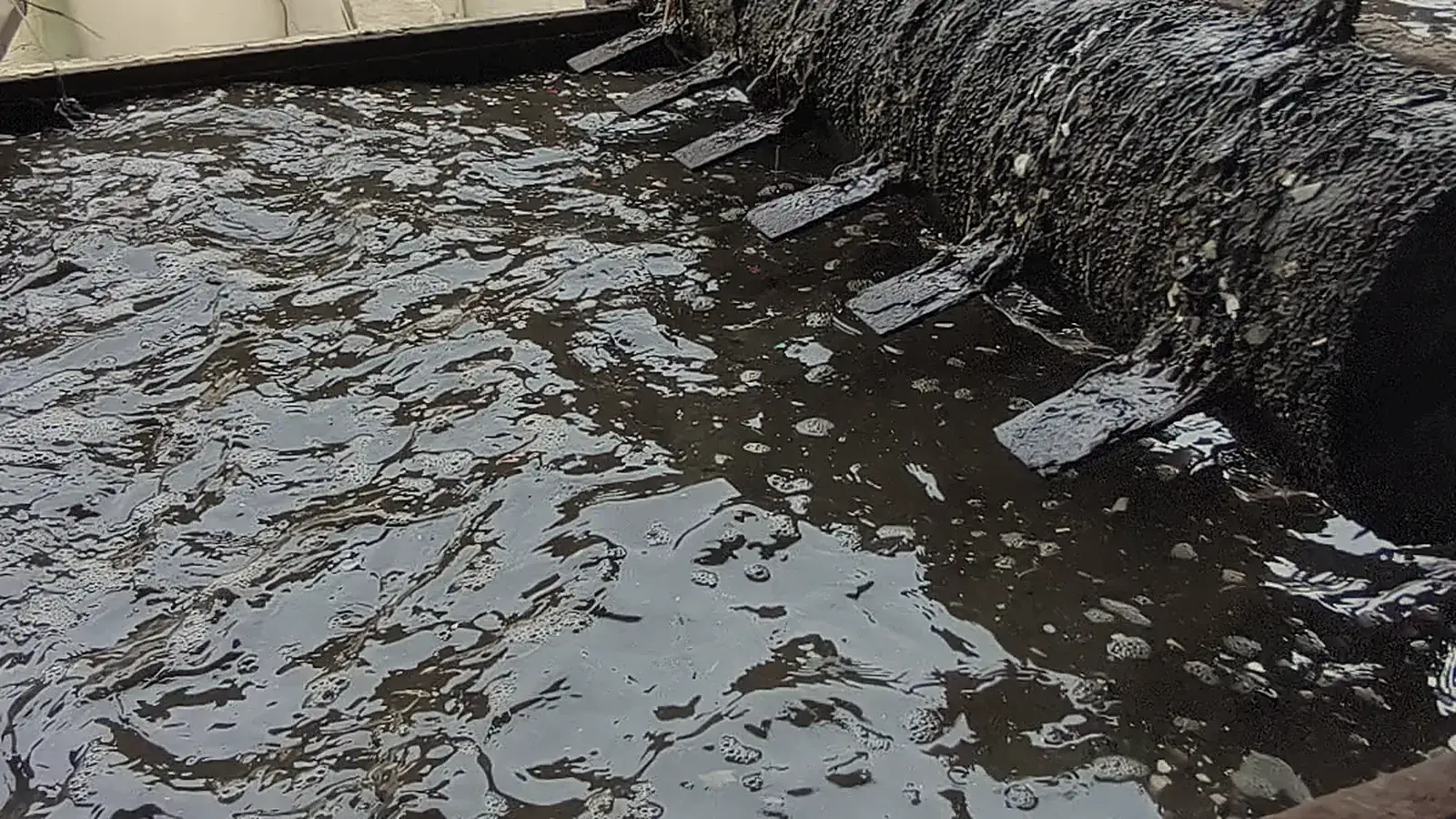 Plastic scrap flakes churned through the water of a washing tank before they are made into resin pellets, in Dayatas Profab's production footage