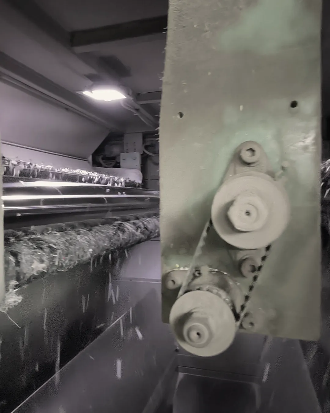 Inside a sorting machine: plastic flakes running over the rollers beside a drive pulley