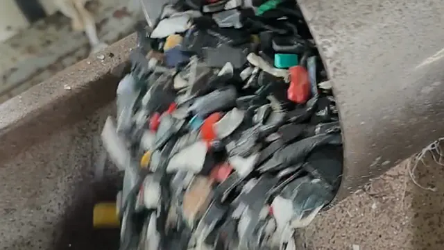 Crushed plastic flakes sliding out of a chute, close up