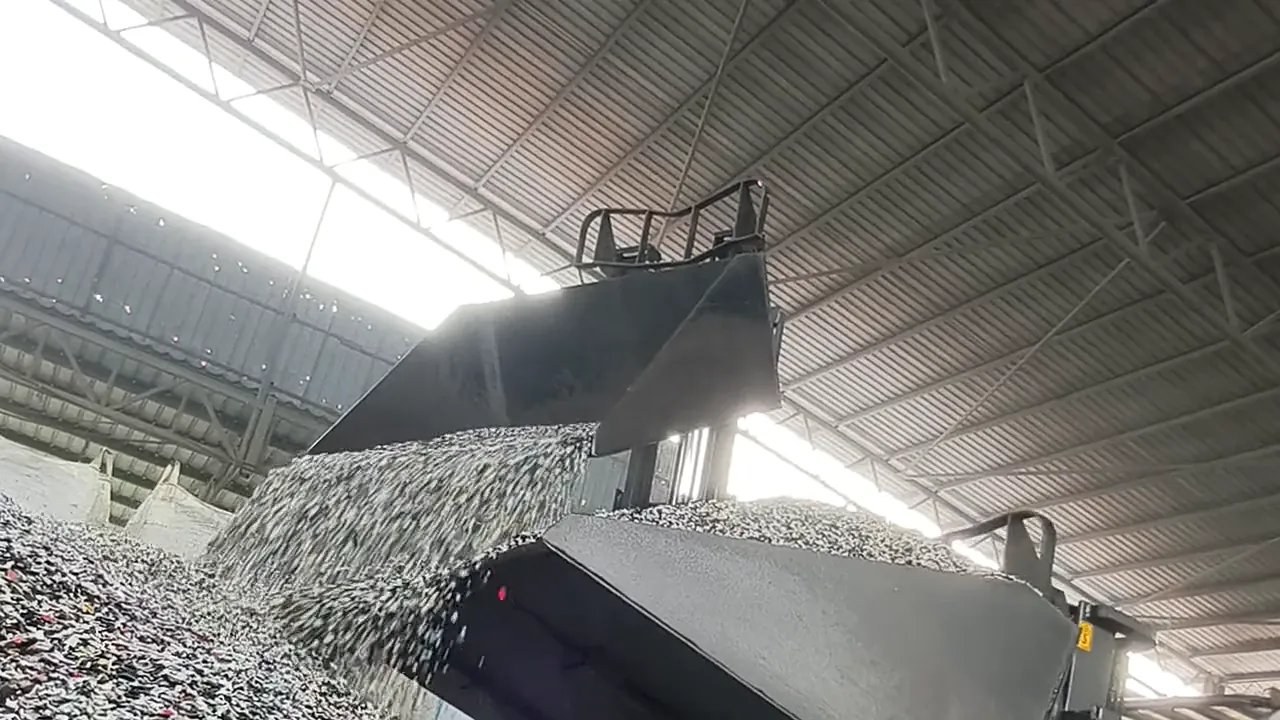 A loader bucket tipping crushed plastic flakes onto the stockpile