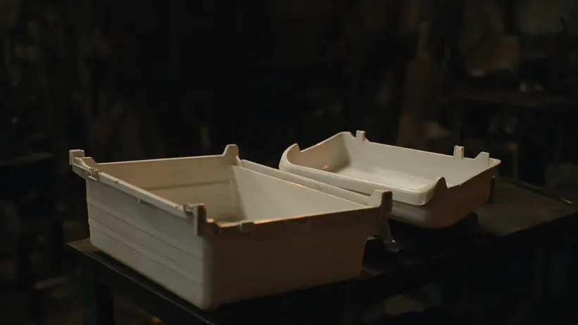 White moulded refrigerator drawer and tray on a dark workbench (illustration)